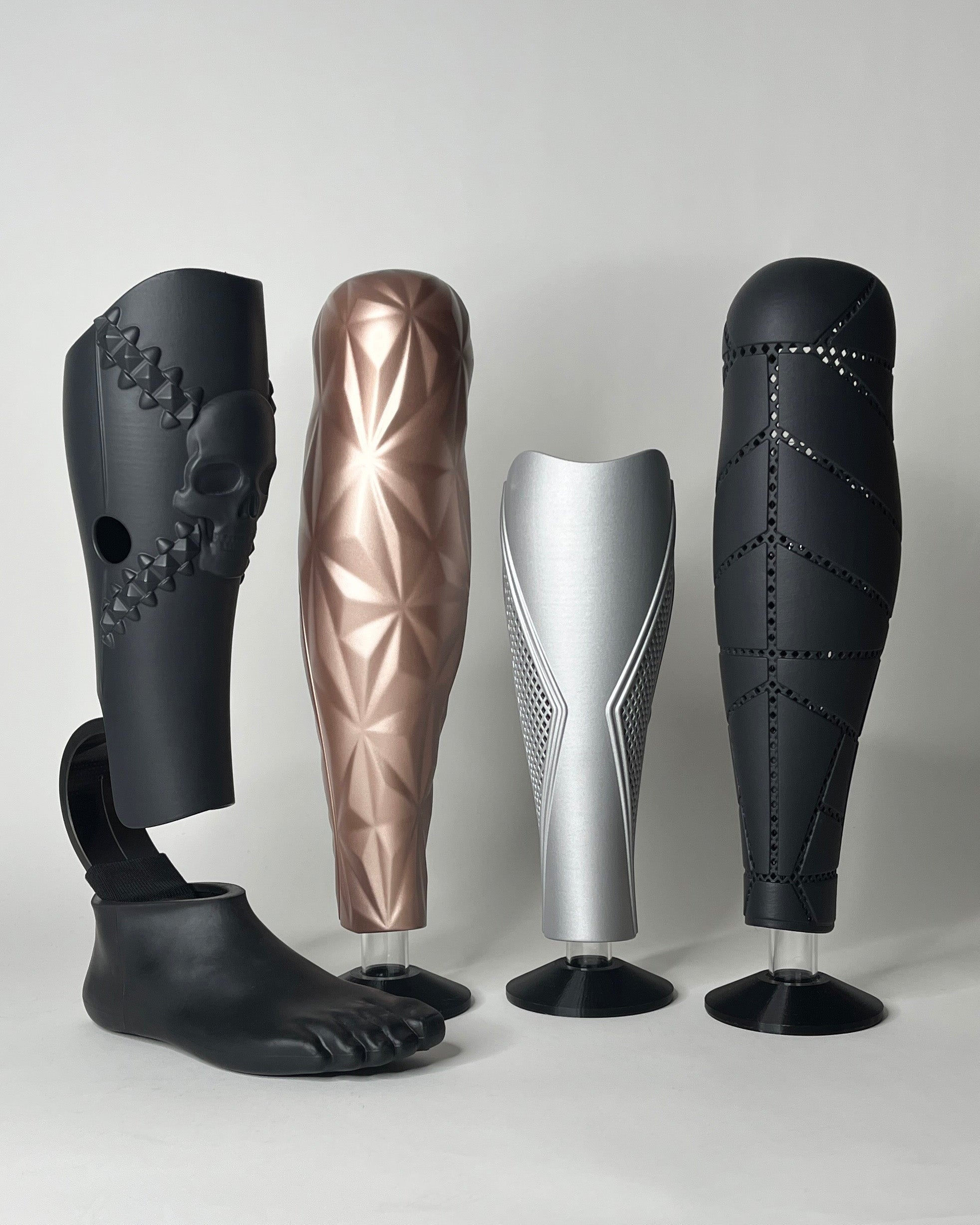 Four prosthetic legs of different designs and colors on a white background