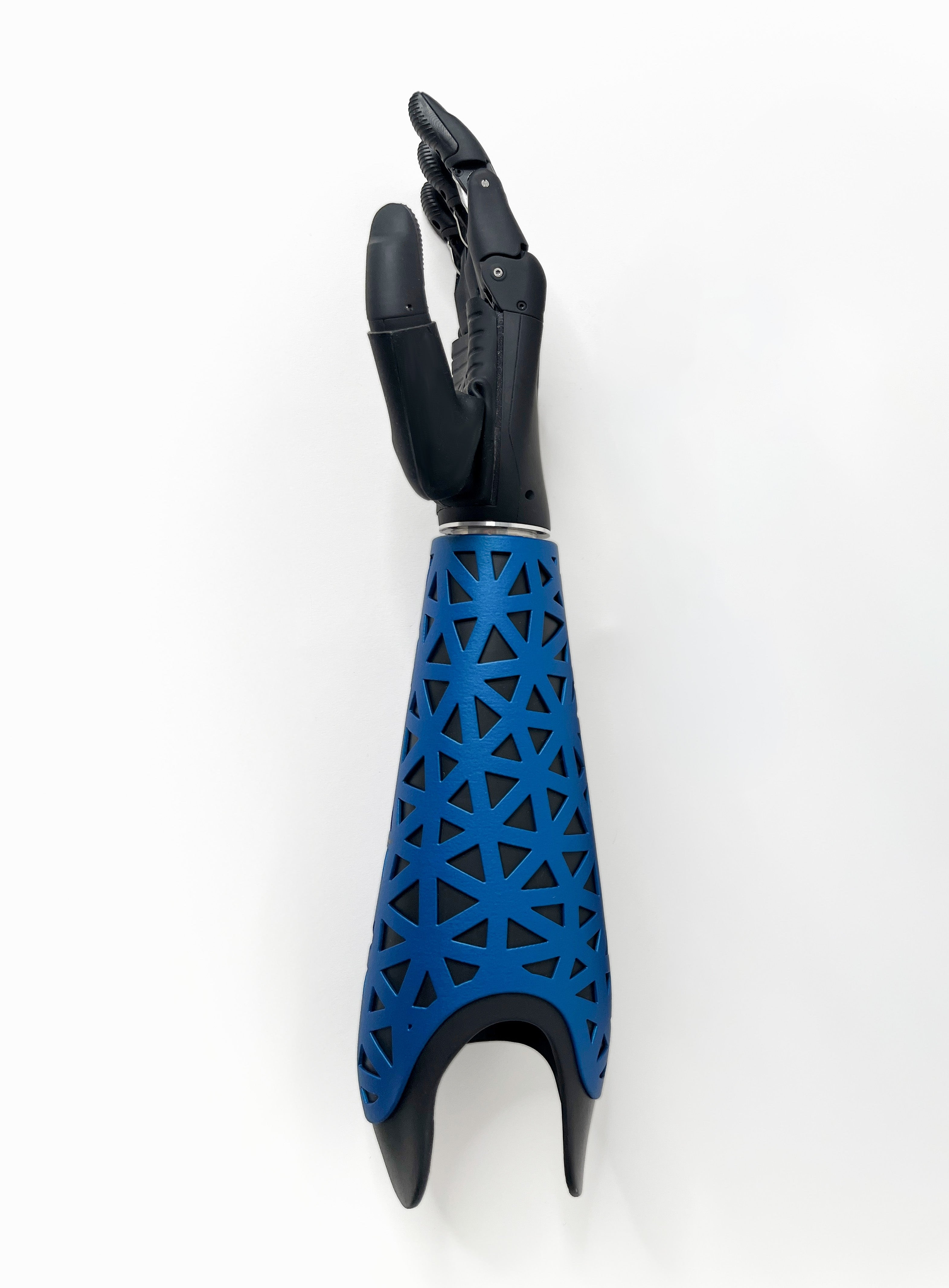 A prosthetic arm with a black articulated hand and a blue geometric lattice-patterned prosthetic cover, shown against a plain white background.