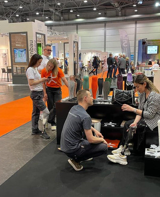 People interacting at a trade fair booth with products on display.